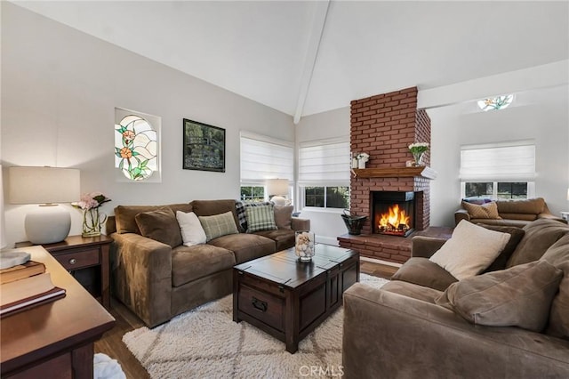 living area with a fireplace, light wood-type flooring, high vaulted ceiling, and beamed ceiling
