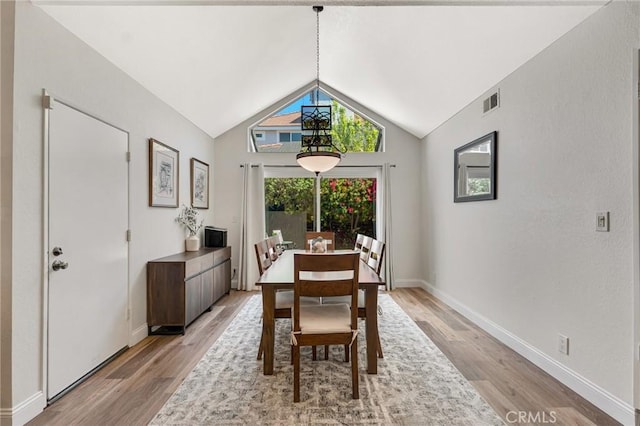 dining room featuring light wood finished floors, vaulted ceiling, and baseboards