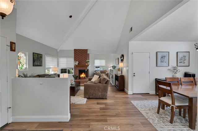 living room with high vaulted ceiling, a fireplace, light wood-style floors, and baseboards