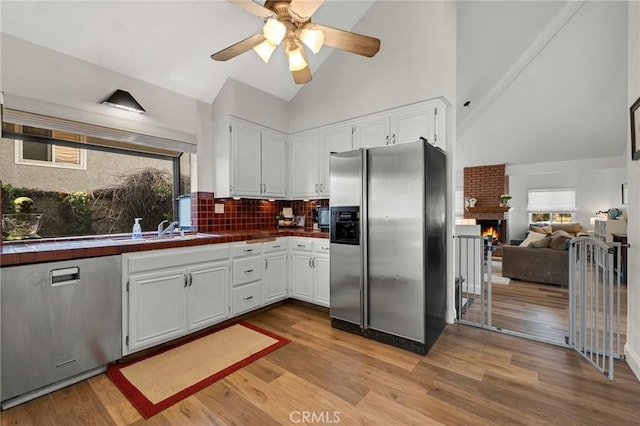 kitchen featuring stainless steel fridge with ice dispenser, tile counters, high vaulted ceiling, ceiling fan, and white cabinetry
