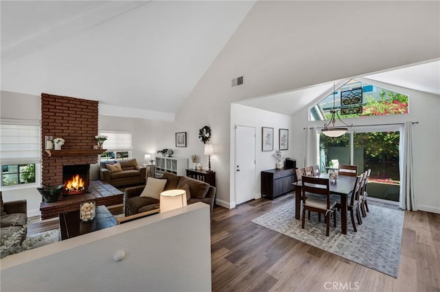 dining area featuring a fireplace, high vaulted ceiling, wood finished floors, and baseboards
