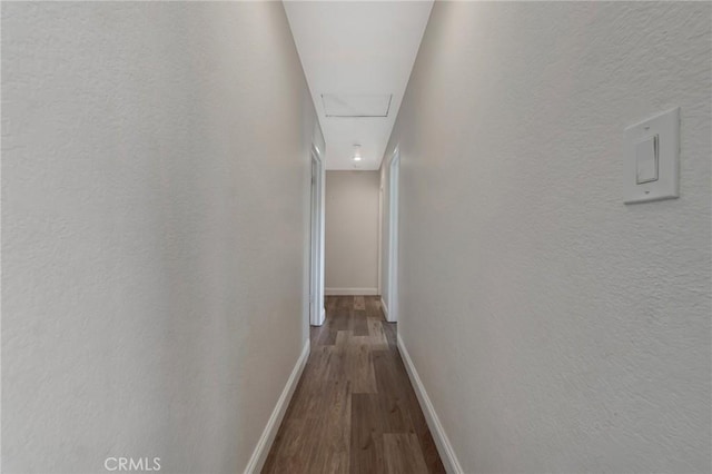 corridor with wood finished floors, baseboards, and attic access