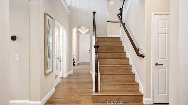 stairs featuring baseboards, wood finished floors, and a high ceiling
