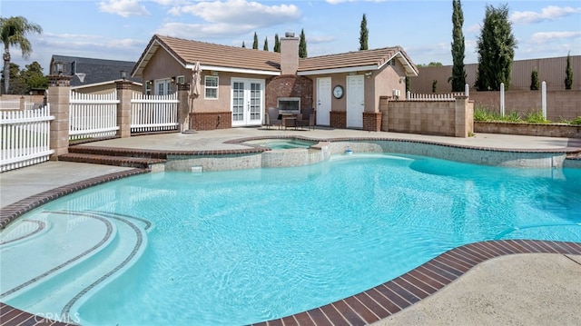 view of swimming pool featuring french doors, a patio, fence, and a pool with connected hot tub