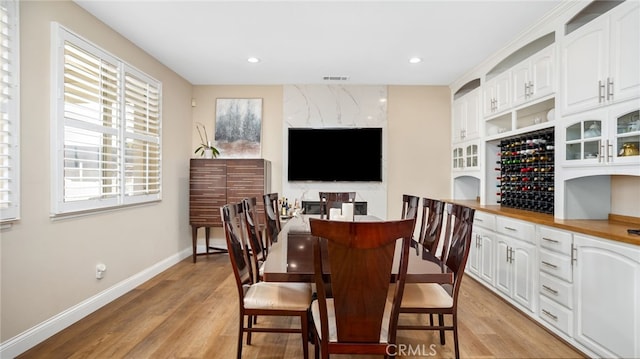 dining room with healthy amount of natural light, light wood-style flooring, baseboards, and recessed lighting
