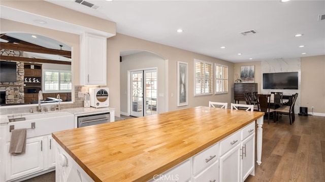 kitchen with wooden counters, arched walkways, open floor plan, recessed lighting, and dishwasher