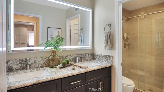 bathroom featuring a stall shower, toilet, and double vanity