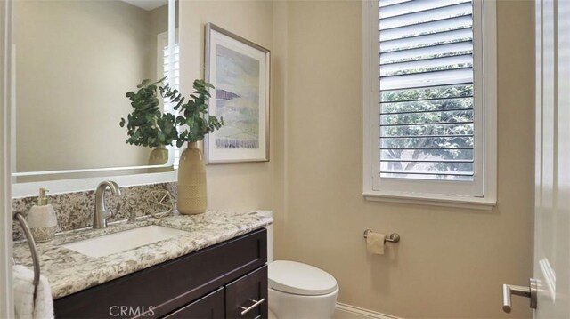 bathroom featuring vanity, toilet, and baseboards