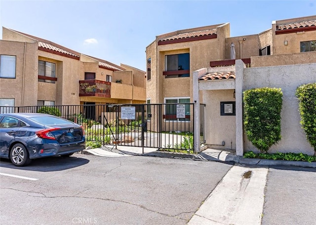 13100 Gilbert St Unit 28, Garden Grove, CA 92844 - view of front of home with a tiled roof, uncovered parking, stucco siding, and a gate