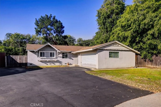 ranch-style home with stucco siding, fence, asphalt driveway, and an attached garage