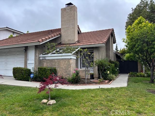 view of front facade with a chimney, an attached garage, and a front yard