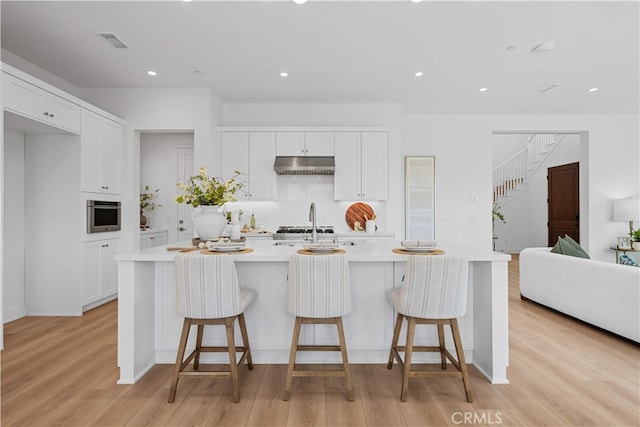 270 Maricopa, Irvine, CA 92618 - kitchen featuring under cabinet range hood, light countertops, light wood finished floors, white cabinets, and recessed lighting