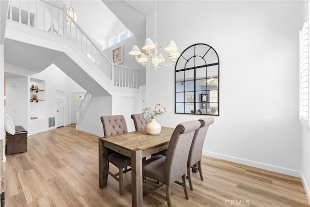 64 Camino, San Jose, San Clemente, CA 92672 - dining room featuring a towering ceiling, stairs, baseboards, light wood-type flooring, and a chandelier