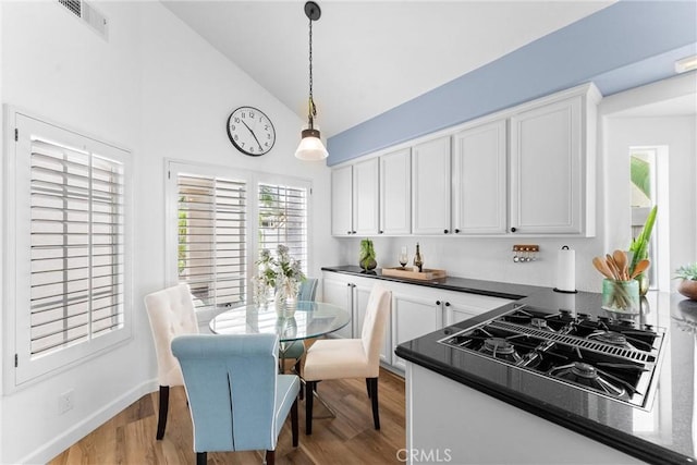 64 Camino, San Jose, San Clemente, CA 92672 - kitchen featuring dark countertops, white cabinets, high vaulted ceiling, light wood-style floors, and pendant lighting