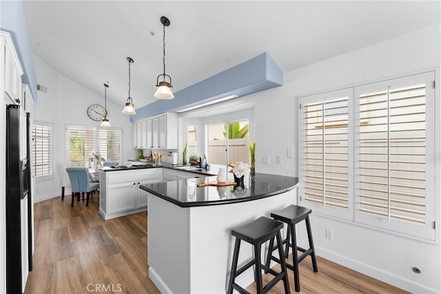 64 Camino, San Jose, San Clemente, CA 92672 - kitchen featuring a peninsula, wood finished floors, white cabinets, dark countertops, and black fridge