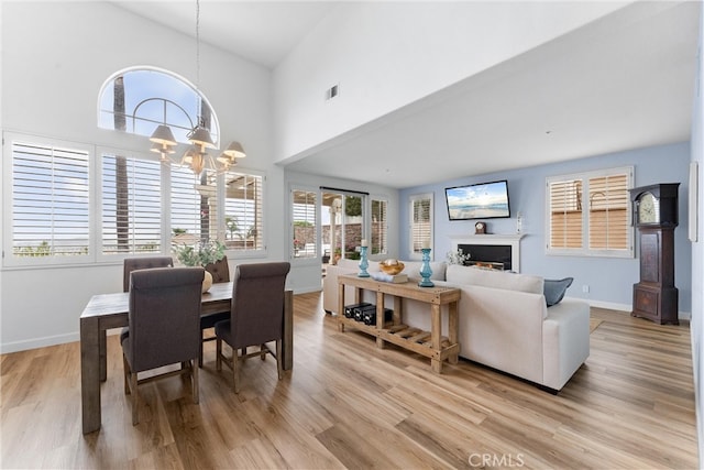 64 Camino, San Jose, San Clemente, CA 92672 - dining room featuring light wood-style floors, a chandelier, a fireplace, high vaulted ceiling, and baseboards
