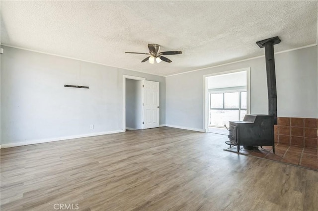 1561 Old Woman Springs Rd, Yucca Valley, CA 92284 - unfurnished living room with wood finished floors, a ceiling fan, a wood stove, a textured ceiling, and crown molding