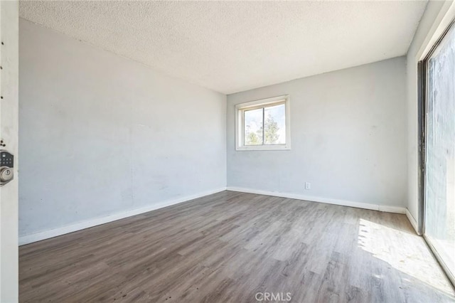 1561 Old Woman Springs Rd, Yucca Valley, CA 92284 - empty room with wood finished floors, a textured ceiling, and baseboards