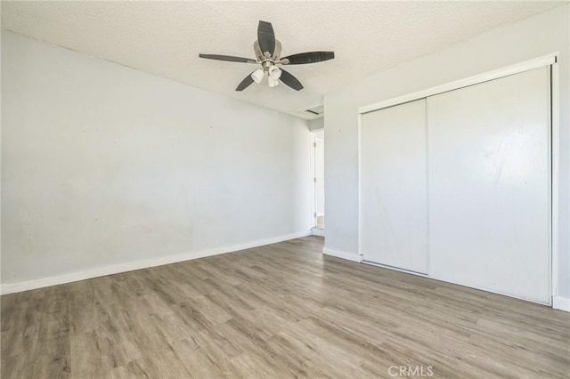 1561 Old Woman Springs Rd, Yucca Valley, CA 92284 - unfurnished bedroom with wood finished floors, a closet, a textured ceiling, baseboards, and a ceiling fan