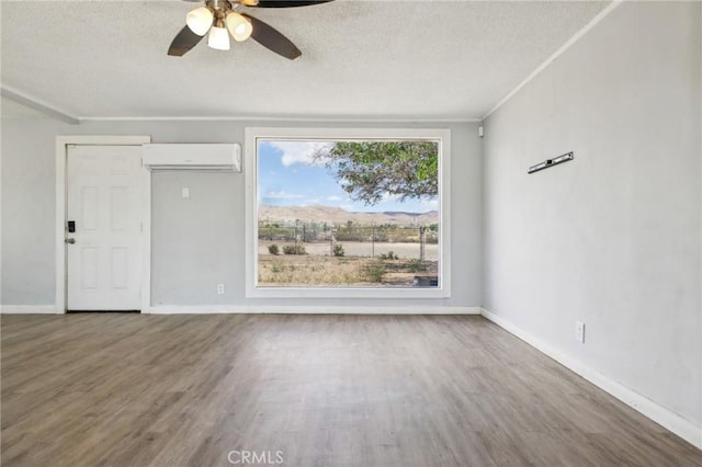 1561 Old Woman Springs Rd, Yucca Valley, CA 92284 - empty room with a wall mounted air conditioner, a textured ceiling, a ceiling fan, wood finished floors, and baseboards