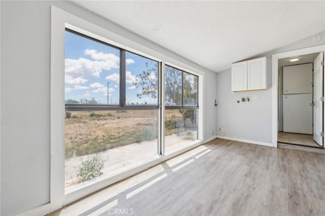 1561 Old Woman Springs Rd, Yucca Valley, CA 92284 - unfurnished living room featuring a textured ceiling, light wood-style floors, lofted ceiling, and baseboards