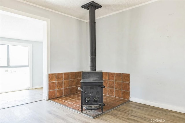 1561 Old Woman Springs Rd, Yucca Valley, CA 92284 - detailed view of a wood stove, wood finished floors, ornamental molding, baseboards, and a textured ceiling