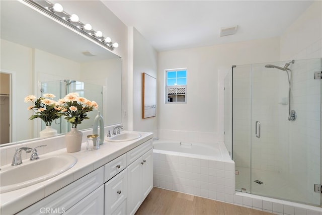 full bathroom with a shower stall, wood finished floors, a garden tub, and double vanity