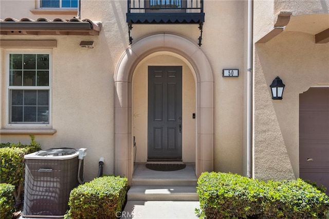entrance to property with central AC unit and stucco siding