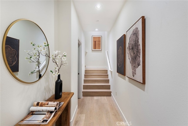 hallway featuring light wood-type flooring, recessed lighting, stairs, and baseboards