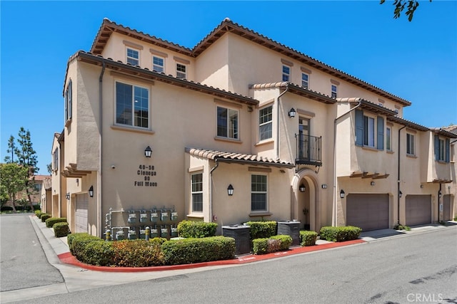 view of front of home featuring an attached garage, a balcony, and stucco siding