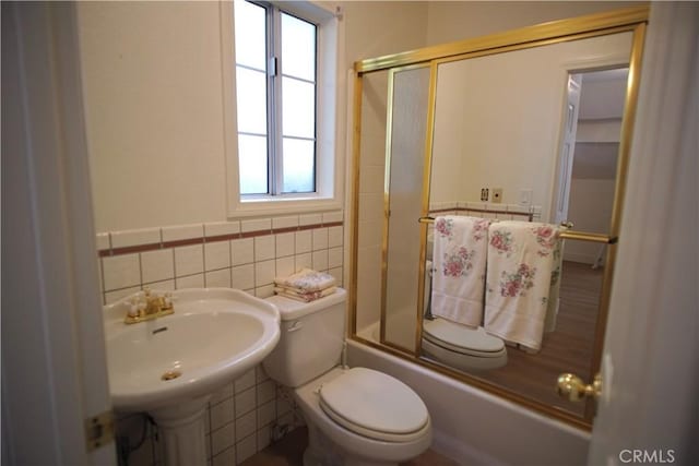 319 Dorn Dr, Crestline, CA 92325 - bathroom with tile walls, toilet, a sink, shower / bath combination with glass door, and a wainscoted wall
