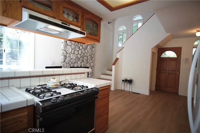 319 Dorn Dr, Crestline, CA 92325 - kitchen with black gas stove, under cabinet range hood, tile counters, and brown cabinetry