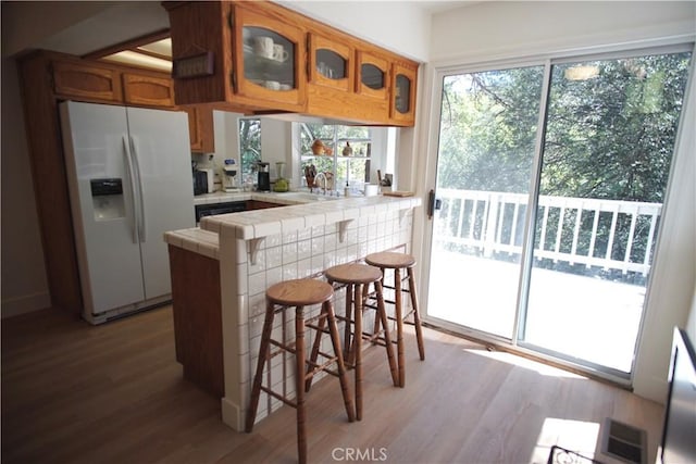 319 Dorn Dr, Crestline, CA 92325 - kitchen with white fridge with ice dispenser, tile countertops, wood finished floors, a peninsula, and brown cabinetry
