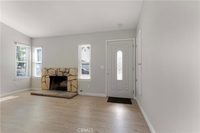 entryway with wood finished floors, baseboards, and a fireplace