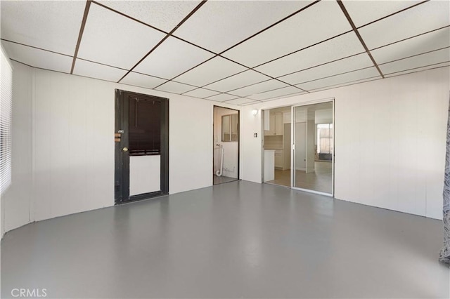 empty room with a drop ceiling and finished concrete floors