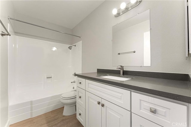 bathroom featuring toilet, wood finished floors, tub / shower combination, and vanity