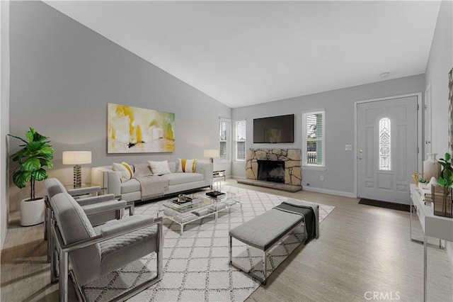 living area with wood finished floors, a fireplace, baseboards, and high vaulted ceiling