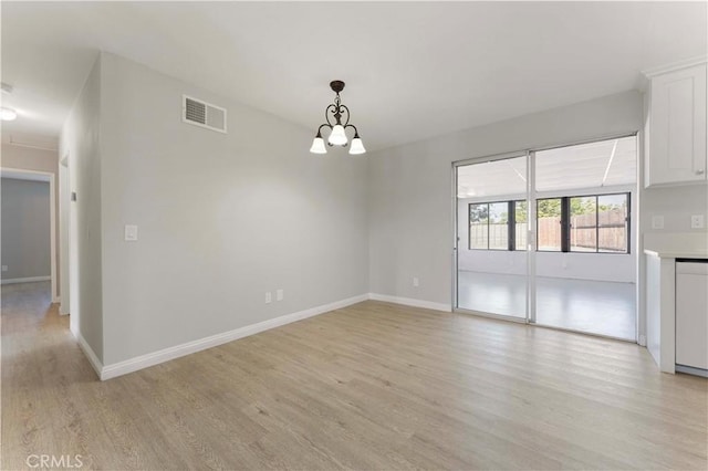 unfurnished dining area with light wood-type flooring, a chandelier, and baseboards