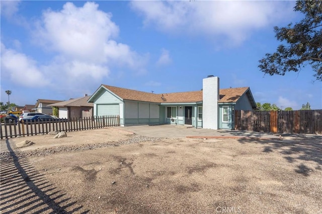 single story home featuring fence, a chimney, an attached garage, and concrete driveway