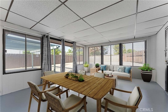 sunroom featuring a paneled ceiling, finished concrete floors, and healthy amount of natural light