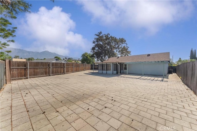 view of front of house with a patio, a sunroom, a fenced backyard, and a mountain view