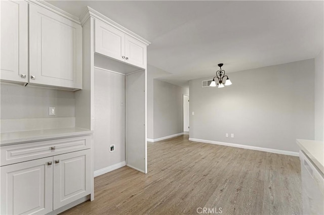 kitchen featuring light wood-type flooring, baseboards, white cabinets, and a chandelier