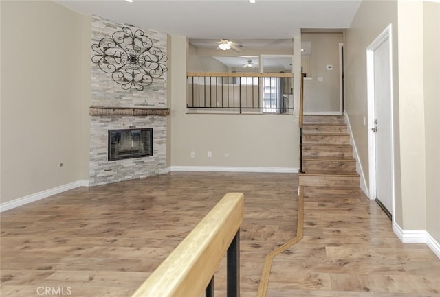 20737 Roscoe Blvd Unit 102, Winnetka, CA 91306 - unfurnished living room featuring a ceiling fan, wood finished floors, a stone fireplace, stairs, and baseboards