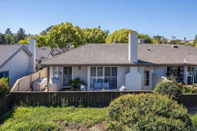 rear view of house with fence, a chimney, and a shingled roof