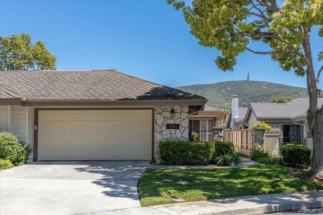view of front facade featuring a garage, driveway, a mountain view, and stone siding