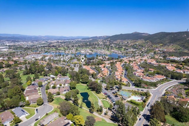 view of property location with a water and mountain view, nearby suburban area, and a local golf course