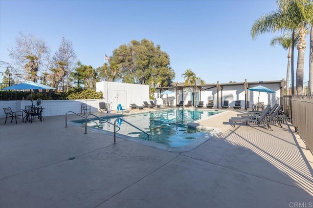 community pool with a patio and fence
