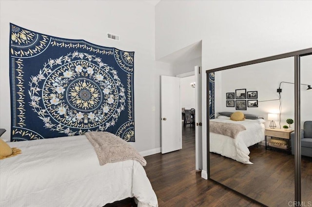 bedroom featuring dark wood finished floors, a high ceiling, and baseboards
