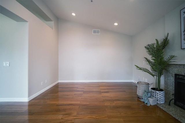 empty room with wood finished floors, lofted ceiling, recessed lighting, a fireplace, and baseboards