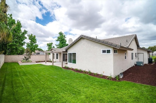 back of house with a patio area, stucco siding, a tiled roof, and a chimney